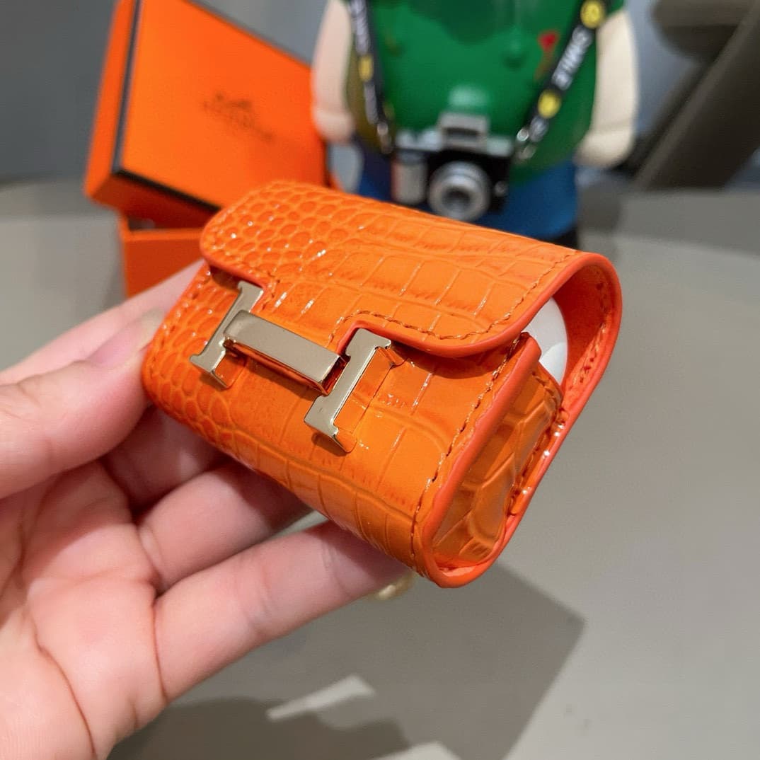 Hermès AirPods cases in crocodile with a gold-tone H clasp